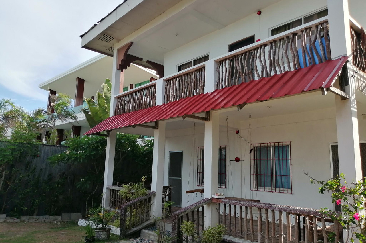 Happy's Homestay two-story building exterior with red roof and tropical garden